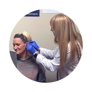 hearing care provider fitting a woman with a hearing aid