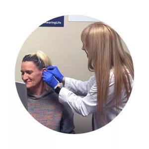 hearing care provider fitting a woman with a hearing aid