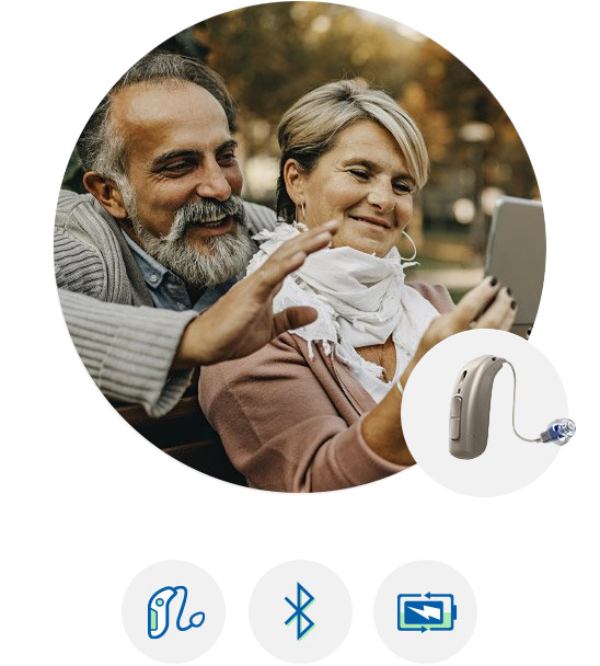 Couple using the Oticon Ruby hearing aid while taking a selfie outdoors