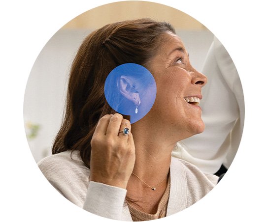 Woman with hearing aid smiling - HearingLife speechbubble icon overlay on ear