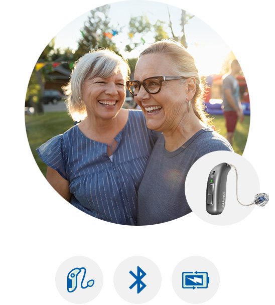 Oticon More hearing aid worn behind the ear of a man outdoors at sunset.