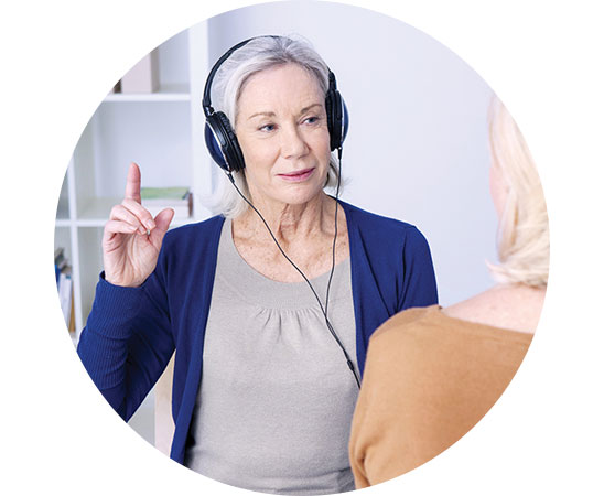 Woman wearing headphones during a hearing test, raising a finger to indicate sound detection.