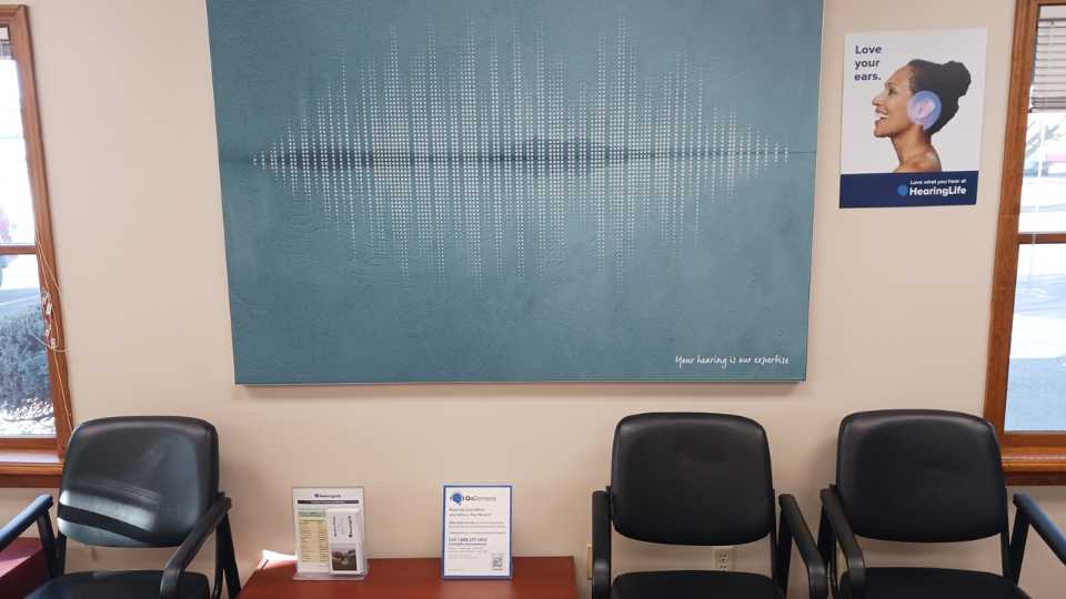 Coldwater hearing center lobby featuring chairs, informational displays, and soundwave-themed artwork.