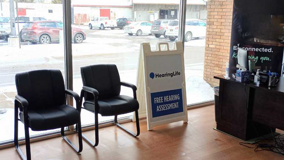 HearingLife Reed City lobby featuring waiting chairs and a sign promoting free hearing assessments.