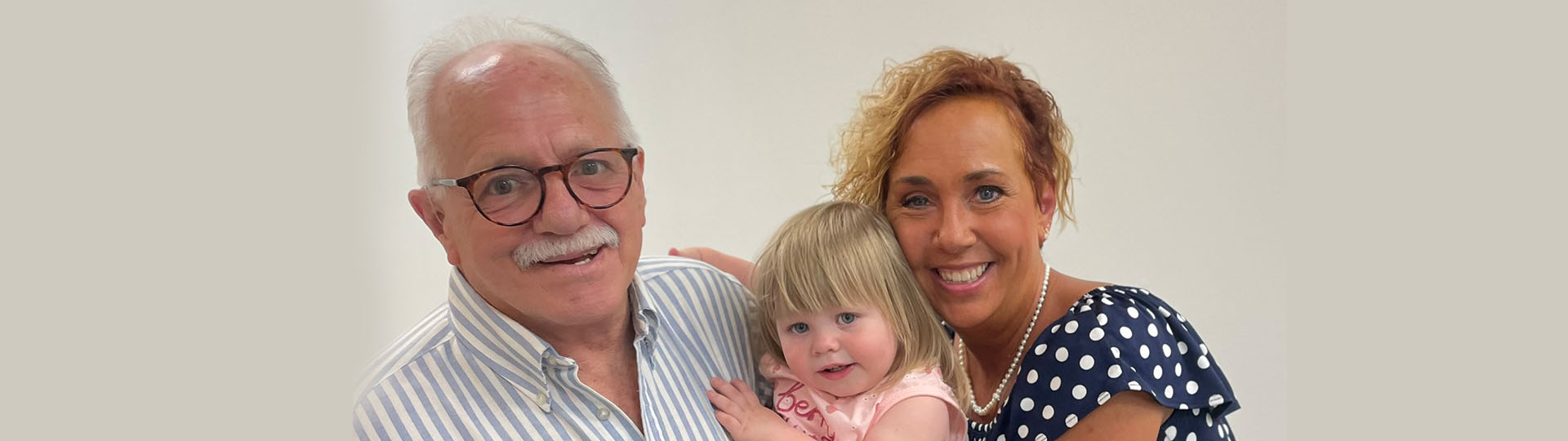 Grandfather enjoying a moment with his young granddaughter and smiling family.