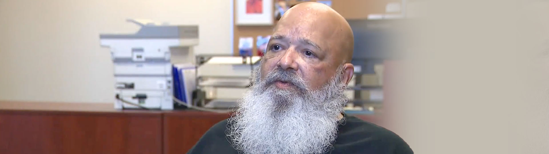 Hearing care patient sitting in an office with a focus on a long, white beard.