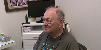 Senior man getting hearing aids adjusted in a clinic setting.