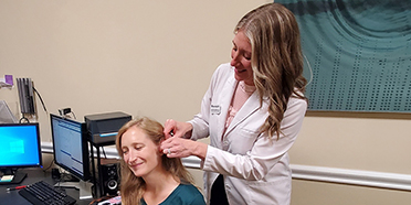 Pittsburgh-area mother receiving a hearing aid fitting from a hearing care specialist