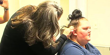 Hearing specialist adjusts hearing aid for mother at Columbus clinic.
