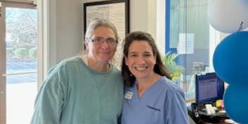 Hearing specialist and patient smiling inside a hearing care clinic.