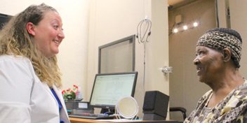 Hearing care specialist consulting with a patient in a clinic setting.