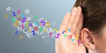 Colorful letters flowing into a hand cupped around an ear, symbolizing auditory perception and hearing.