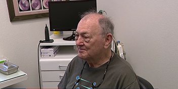 Kenneth Trinoskey fitted with hearing aids in a clinic setting