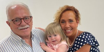 Grandfather embraces a moment with his granddaughter and daughter, highlighting the joy of restored hearing
