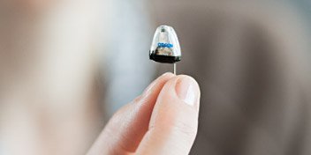 Hand holding a small hearing aid device for testing