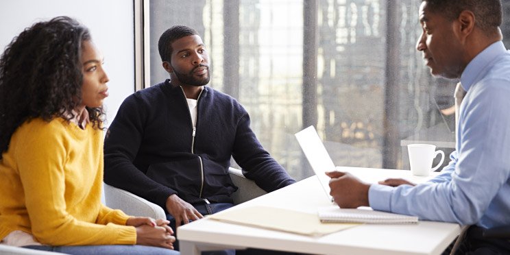 Image shows 3 people talking at a table