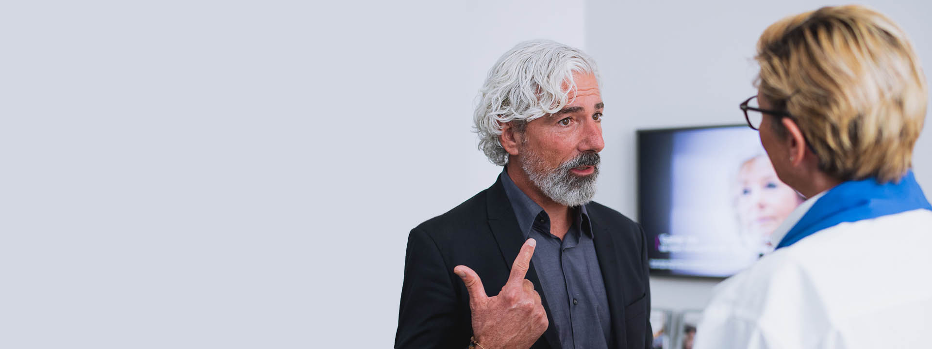 Image shows man talking to audiologist in the clinic