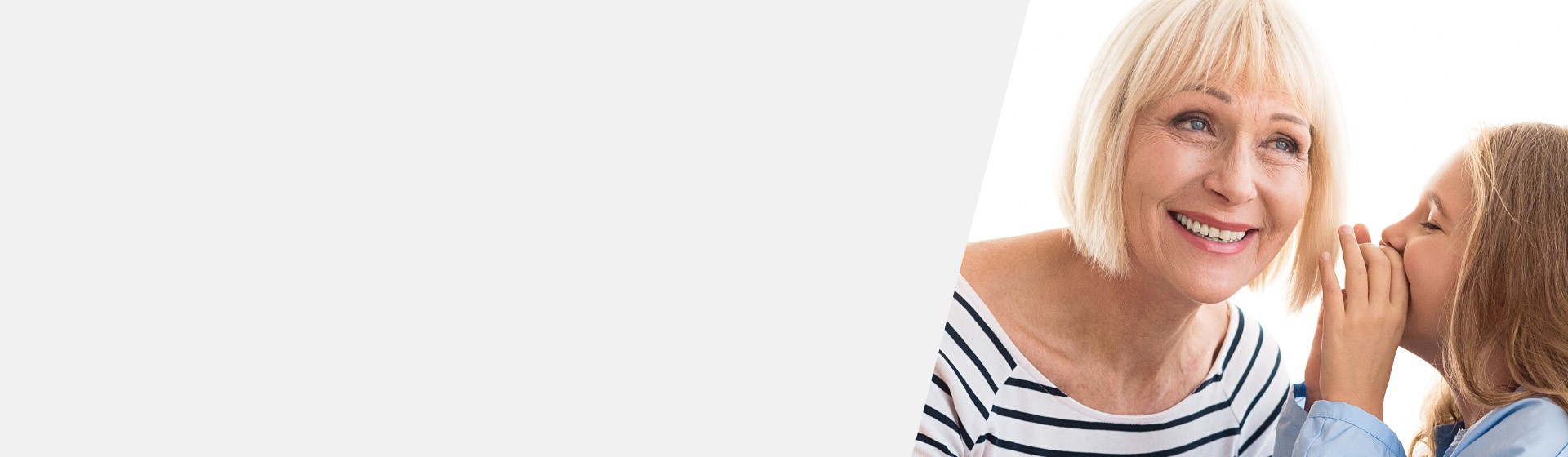 Little girl whispering to an older woman impacted by high-frequency hearing loss.