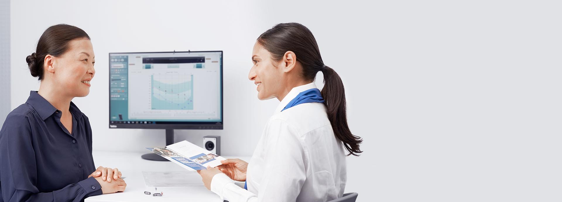 HearingLife hearing care expert consulting a woman with hearing test results displayed on a computer screen.