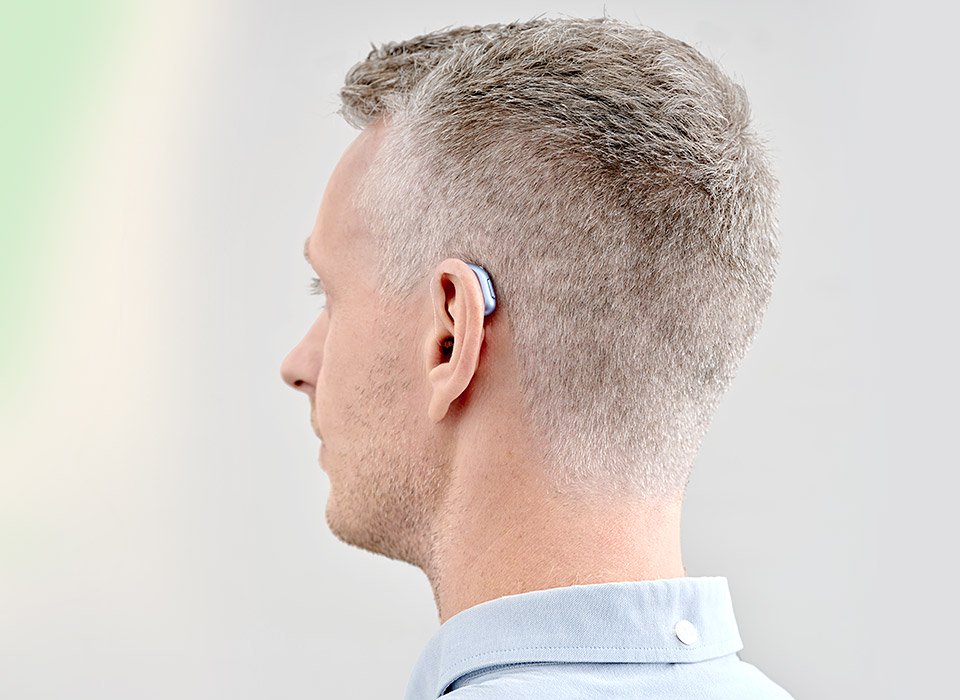 A man wearing a blue Oticon Intent hearing aid