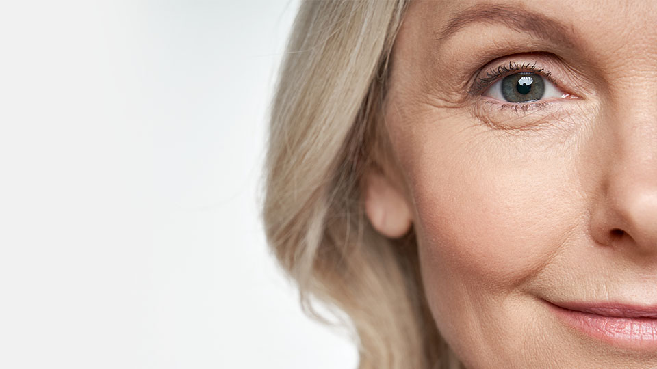 Smiling blonde woman with visible eye and part of her face.