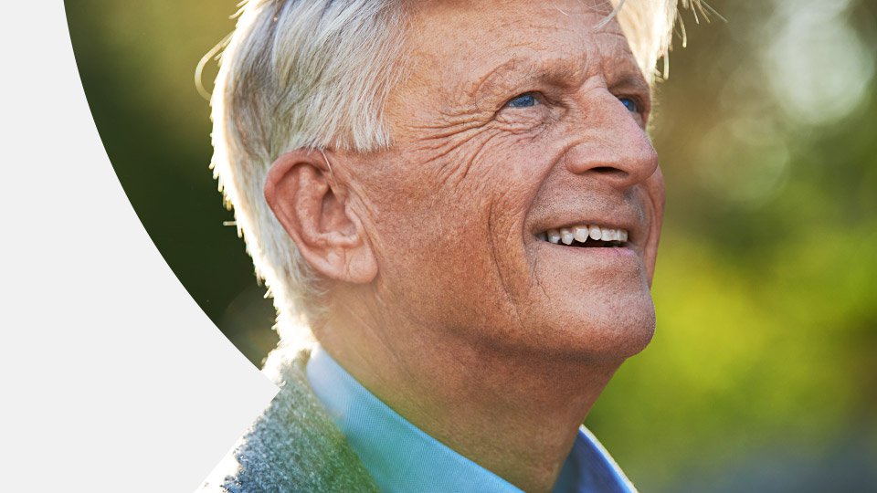 Elderly man with gray hair enjoying the outdoors, emphasizing hearing health and wellness.