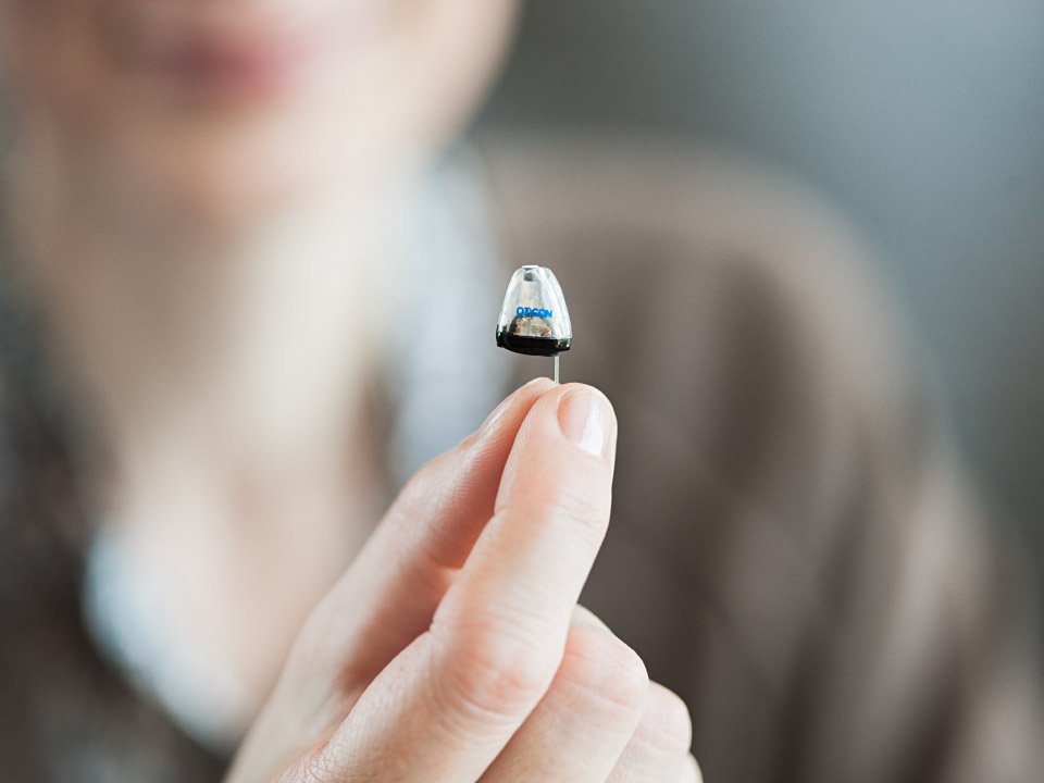 A hand holds a small insect-like robot with text 