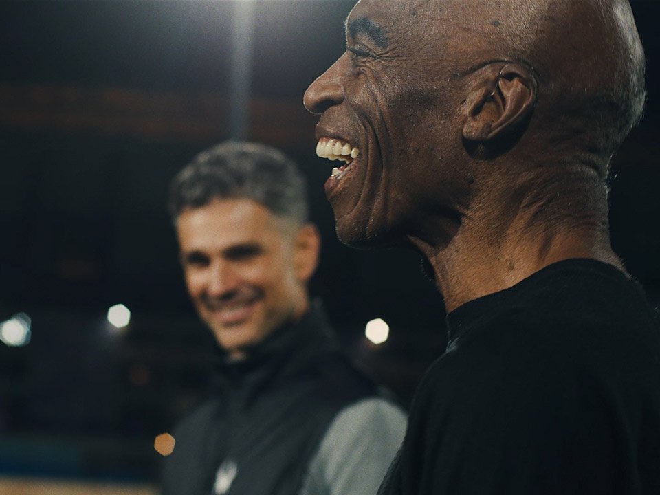 Smiling man in a dimly lit outdoor setting, focusing on his ear.