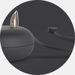 Connecting a hearing aid charger to a power source using the built-in cable.