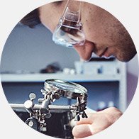 Technician performing hearing aid repair using magnifying tools.