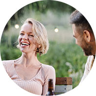 People enjoying an outdoor dinner party with greenery in the background
