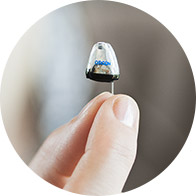 Fingers holding a small hearing aid