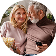 Image shows couple of the sofa holding remote control