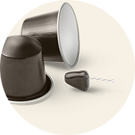A discreet hearing aid resembling a coffee capsule lies next to two dark coffee pods on a beige background, emphasizing the device's compact, inconspicuous design for improved hearing care. No text is present.