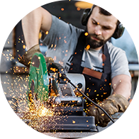 Man wearing protective gear operating a loud power tool with sparks flying.