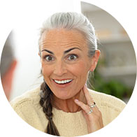 Older woman with gray hair holding her hand near her ear, appearing to focus on a conversation.