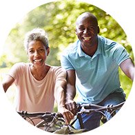 Couple riding bicycles outdoors in a green, sunny environment