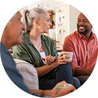 Group of people enjoying a conversation while holding cups in a relaxed setting.