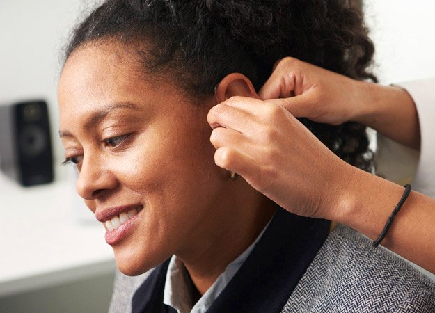 Placing a hearing aid into a woman's ear for improved hearing care