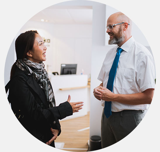 Audiologist providing hearing care advice to a woman in a bright, modern clinic setting