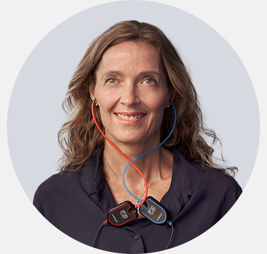 Woman smiling during a hearing test with diagnostic equipment featuring red and blue cables.