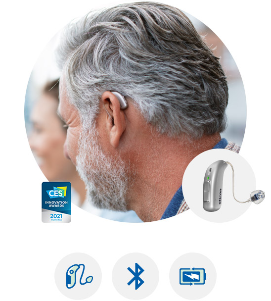 Oticon More hearing aid worn by a man with gray hair, showcasing its discreet design and advanced features.