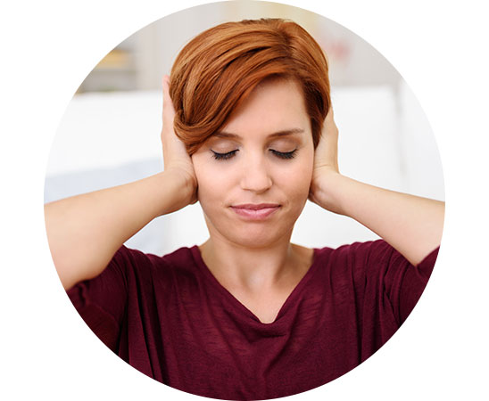 Woman holding her hands over her ears, potentially experiencing sound sensitivity or discomfort.