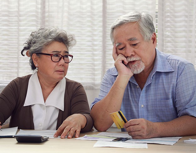 Older adults reviewing financial documents with a credit card at a table.