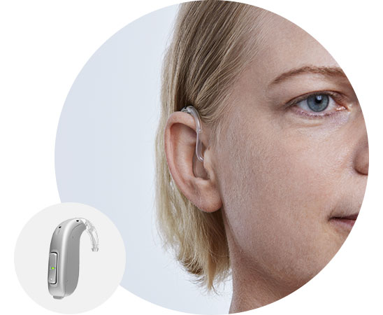 Woman wearing a behind-the-ear hearing aid with close-up of the device.