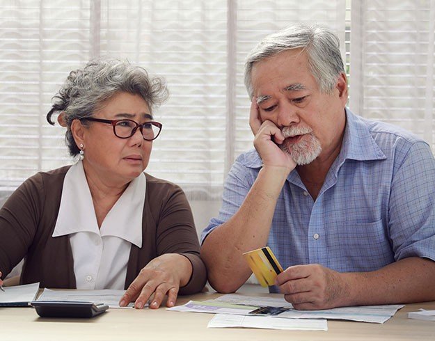 Older couple discussing documents at a table while holding a credit card.