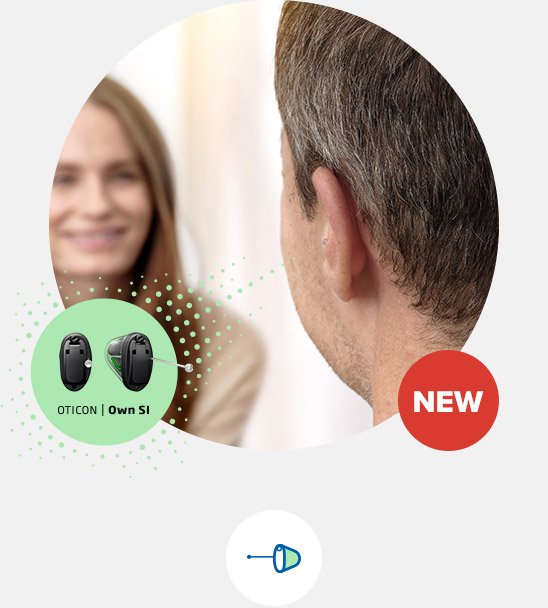 A man wearing an Oticon Own SI hearing aid sits in a hearing clinic, engaging with a blurred individual in a professional setting. Text reads ’OTICON | Own SI’ and ’NEW.’