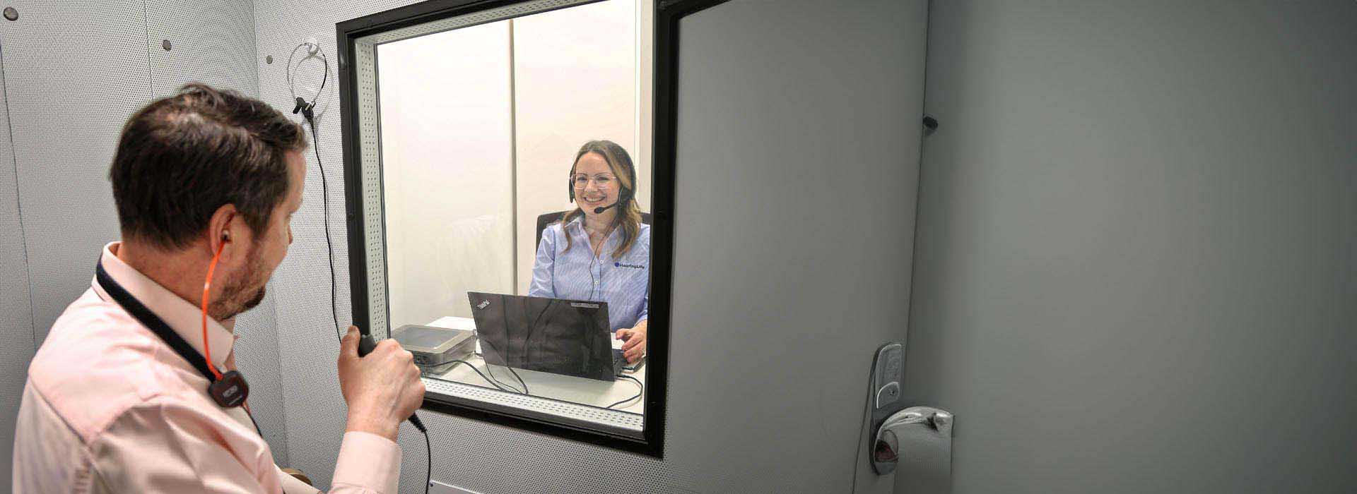 L’image montre une femme avec un casque en train de faire le test auditif en ligne