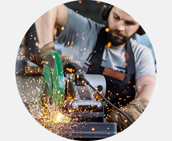 Homme utilisant une meuleuse qui émet des étincelles dans un environnement bruyant.